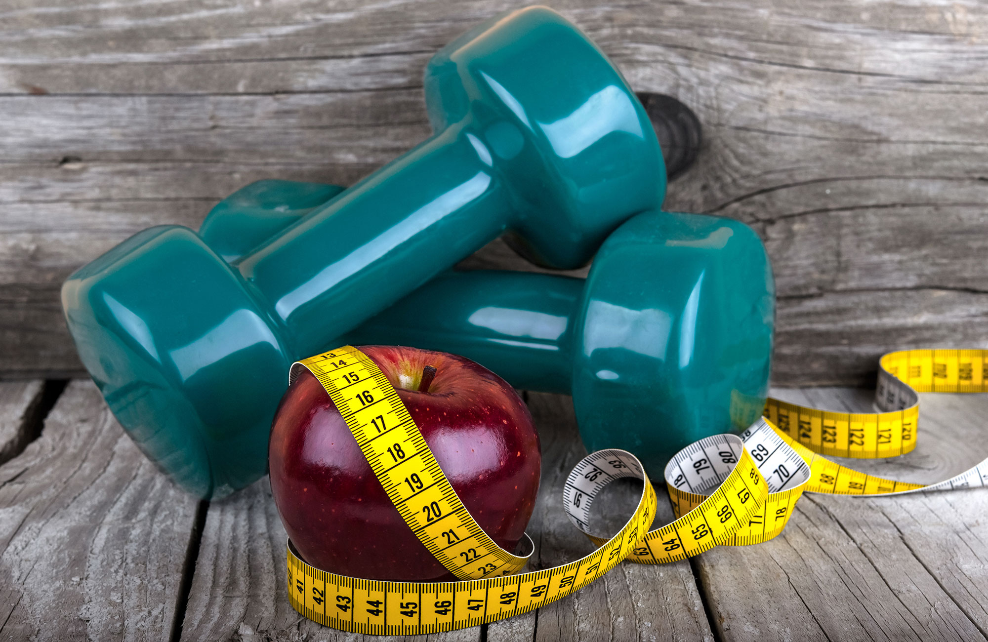Weight loss tools including dumbbells, apple, and measuring tape