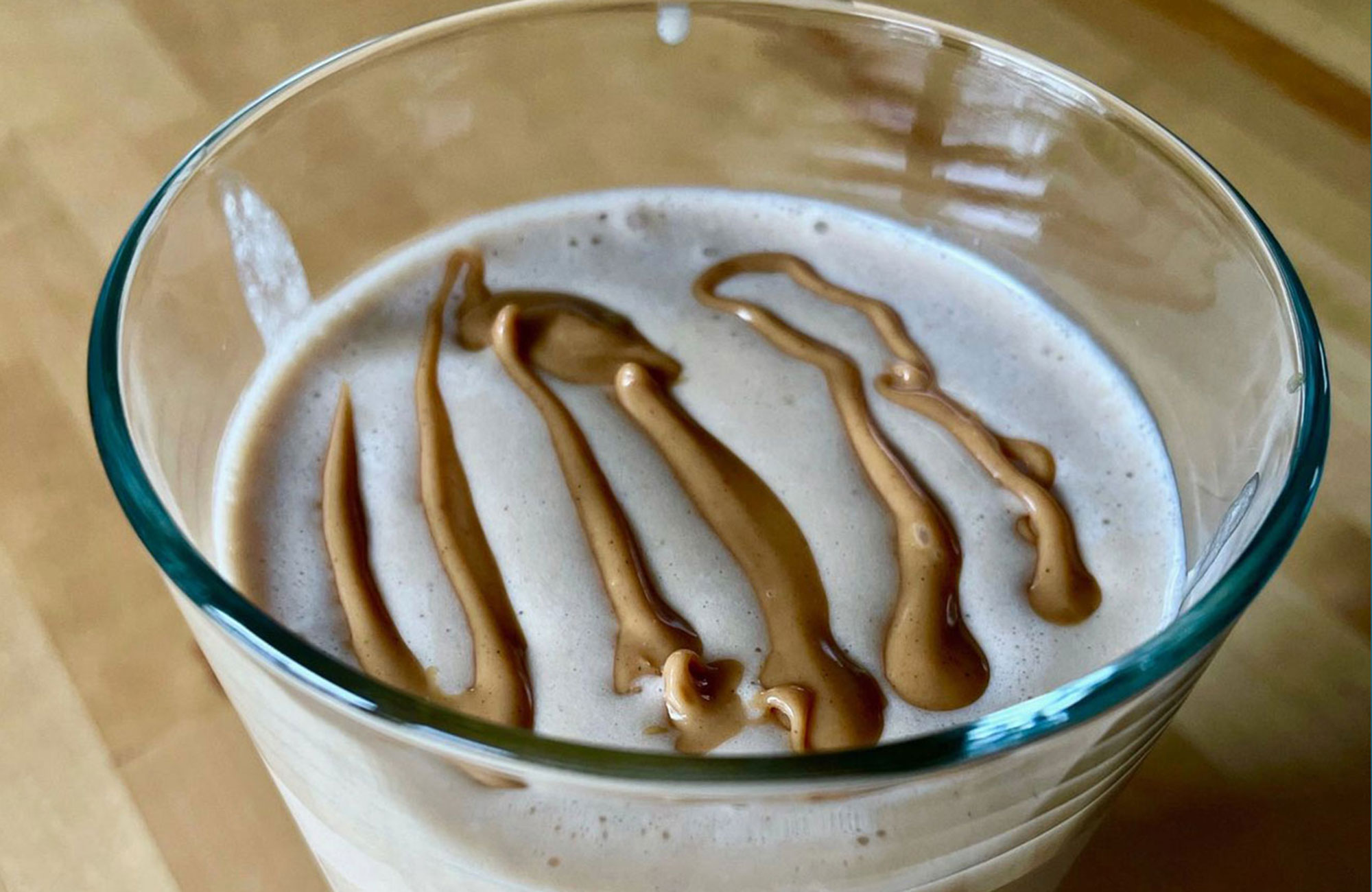 Peanut butter smoothie in a glass with peanut butter drizzle
