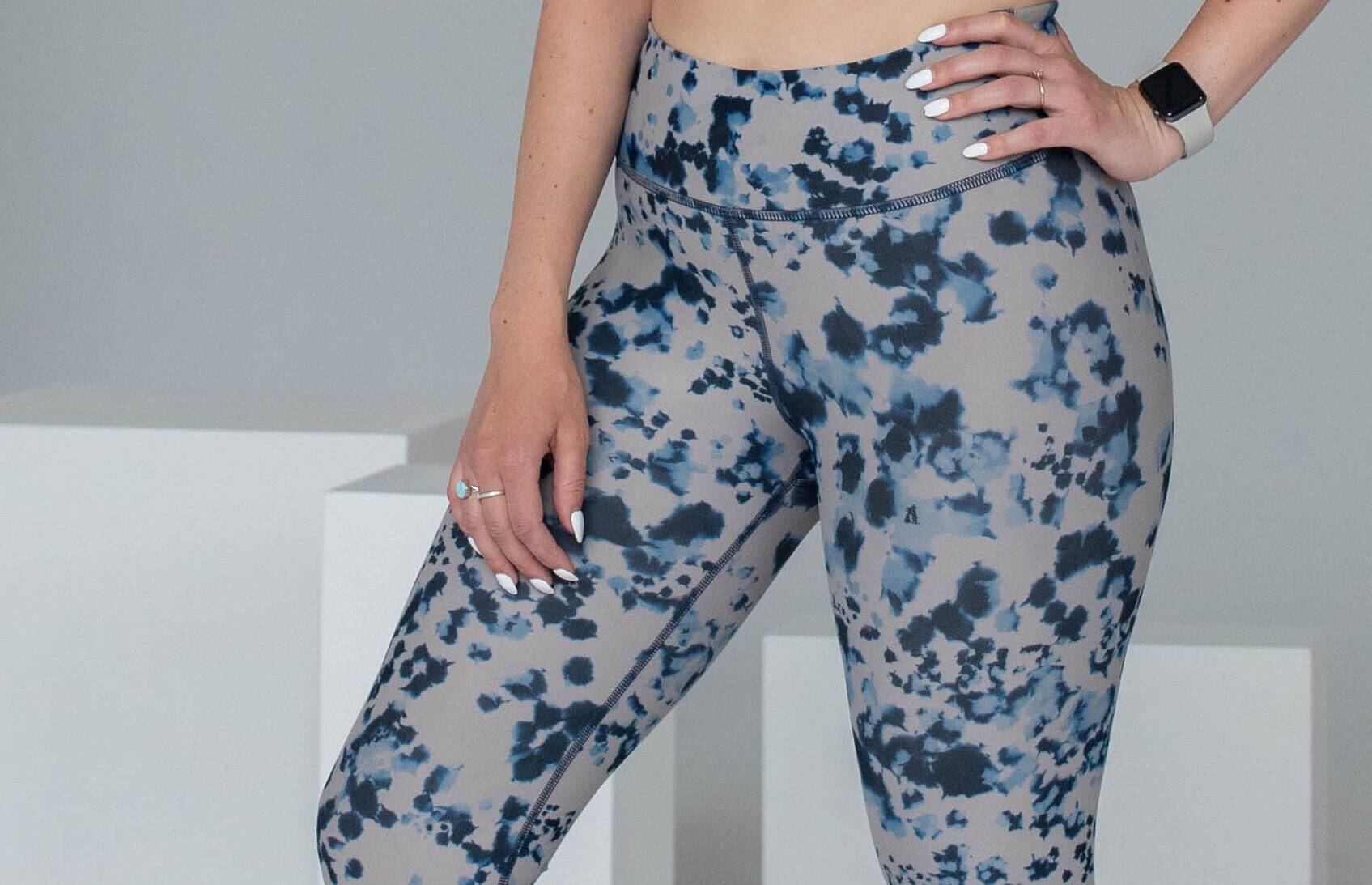 Women wearing a pair of blue spotted leggings with her hand on her hip.