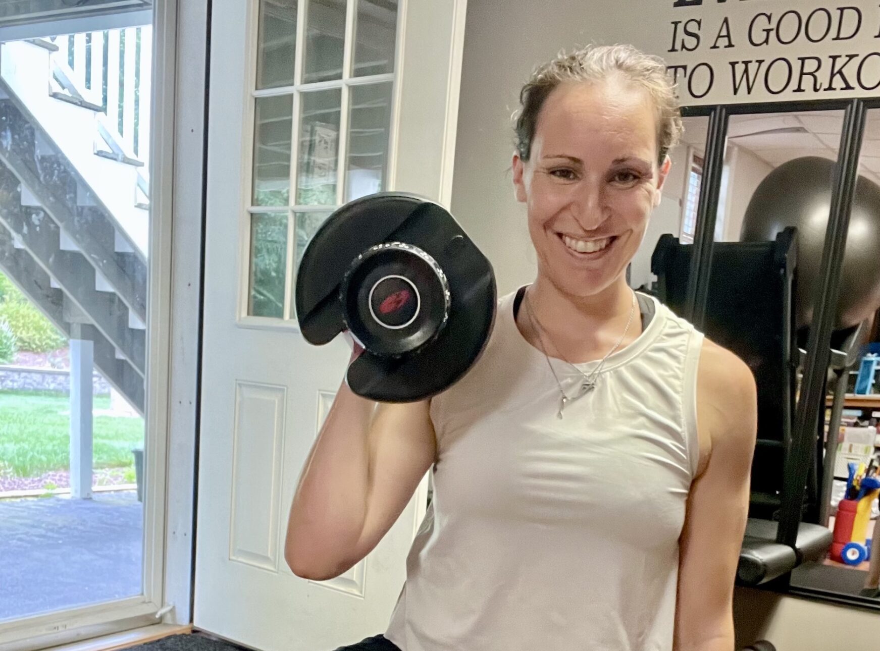 Trainer posting with a dumbbell in her at-home gym