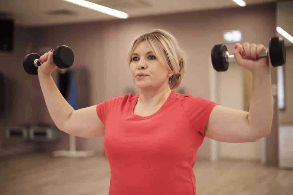 women strength training doing a shoulder press 